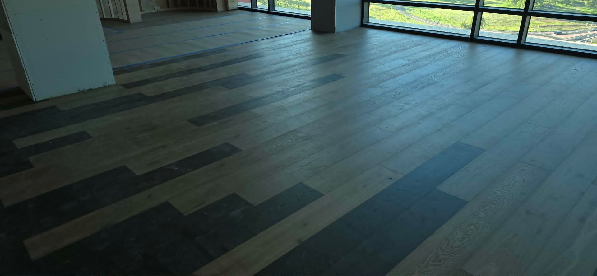 Empty modern room with dark wood flooring and large windows letting in natural light