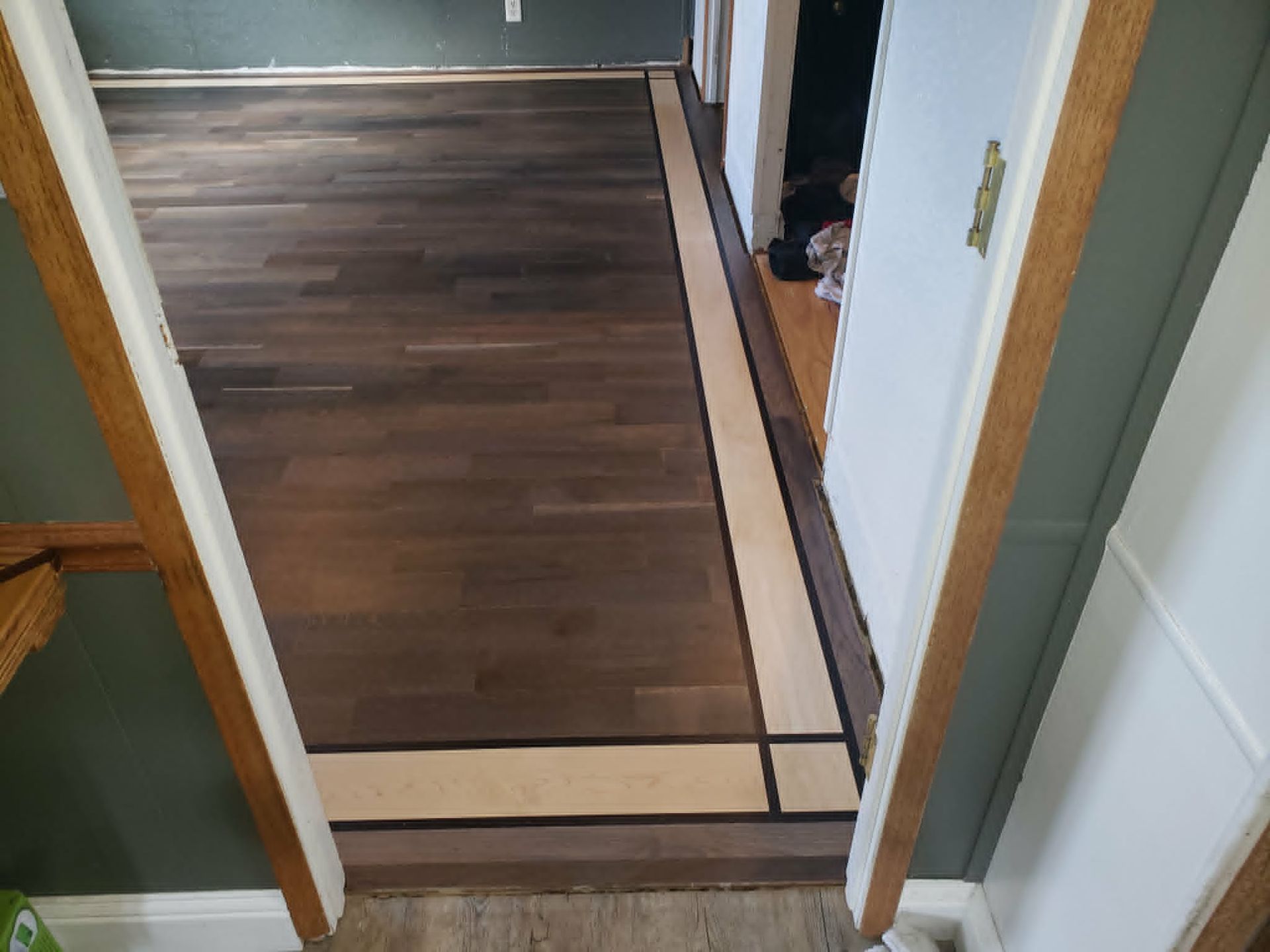 New wood floor installed in a hallway between doorways, with trim and threshold visible