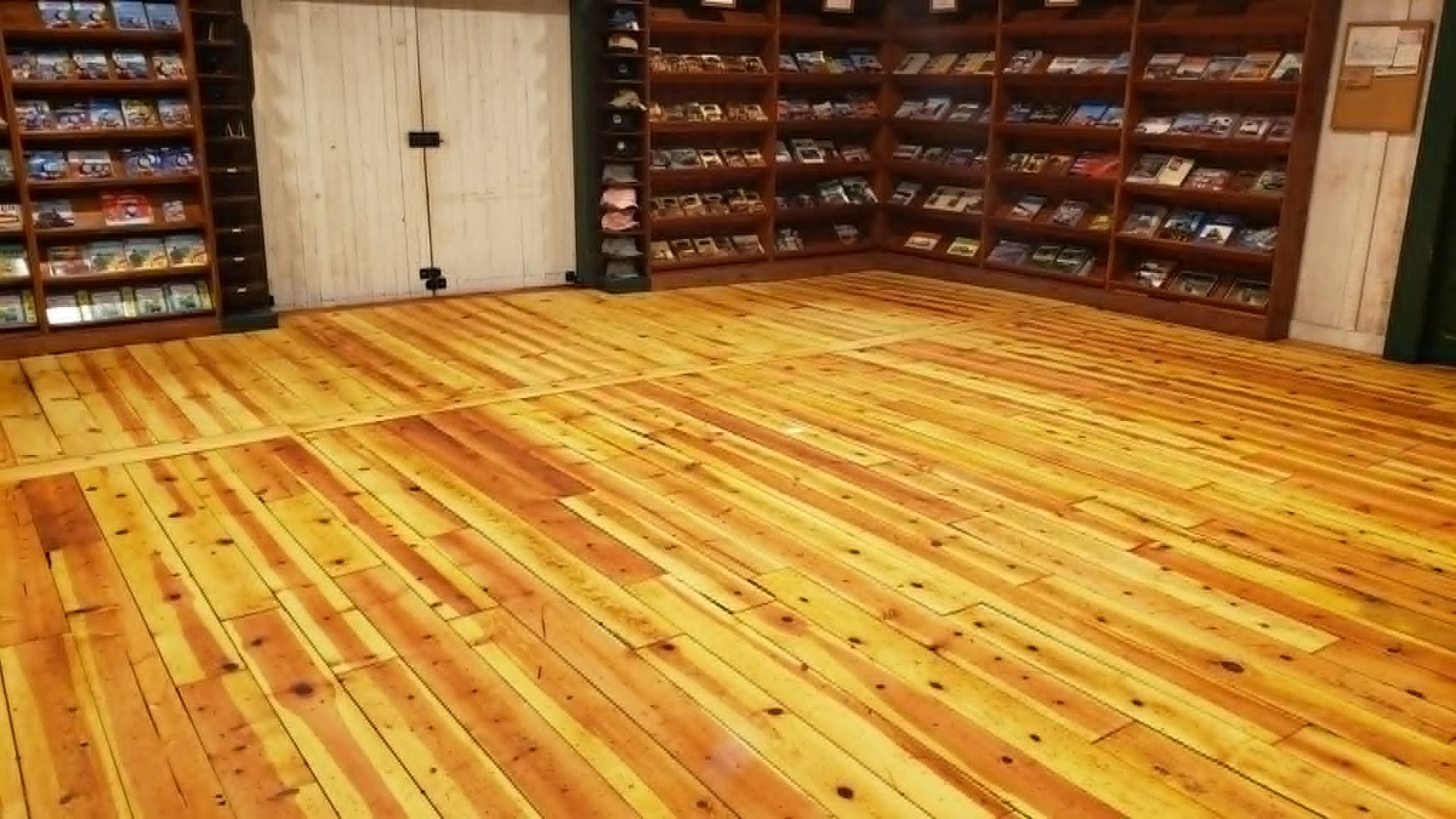 Empty wooden dance studio with polished floor and wall-mounted shelves of shoes or props