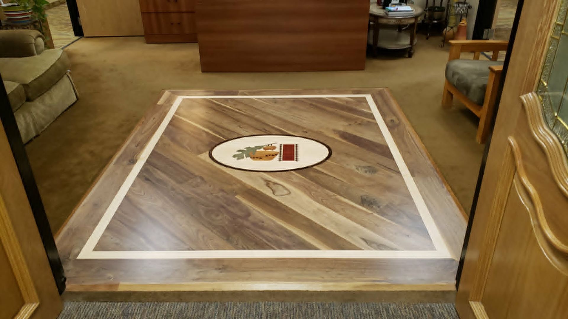Indoor floor display with wood-grain pattern and a round tray centered on it, inside a room