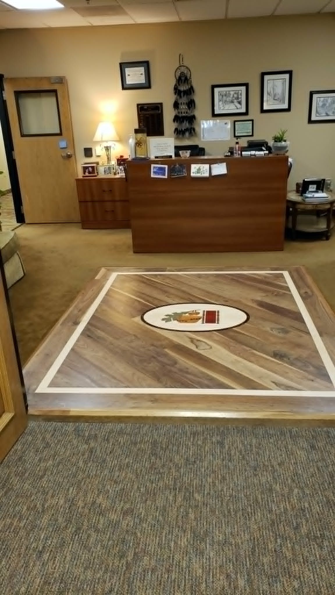 Office lobby with reception desk, framed wall art, and a carpeted floor display in the foreground