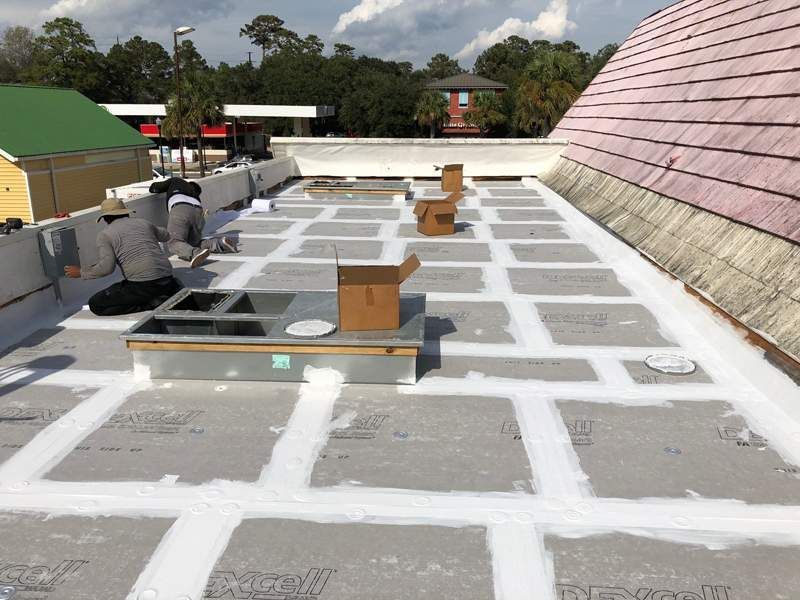 Roofers installing a flat roof with square sections and white sealant.