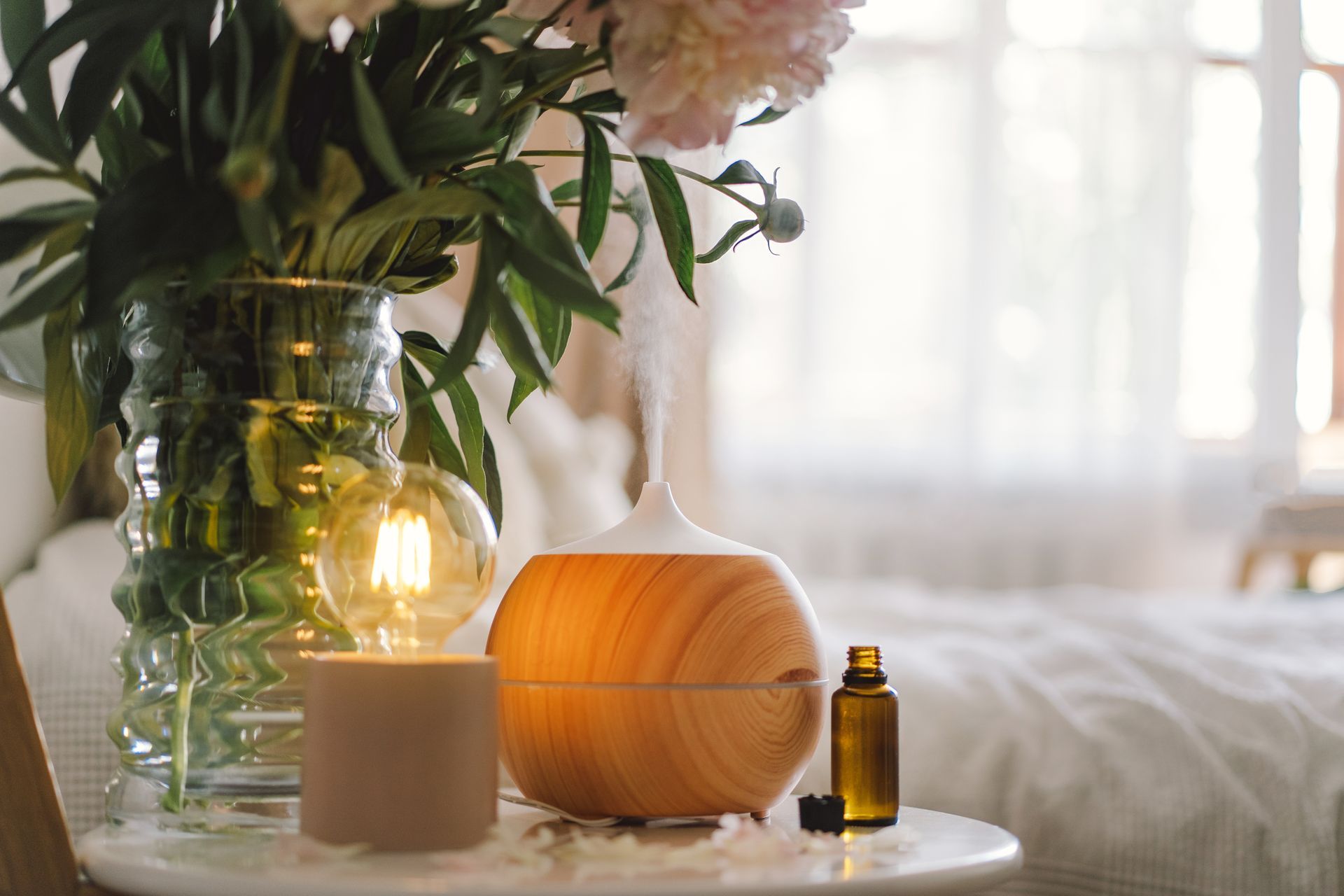 Un diffusore di legno è appoggiato su un tavolo accanto a un vaso di fiori.