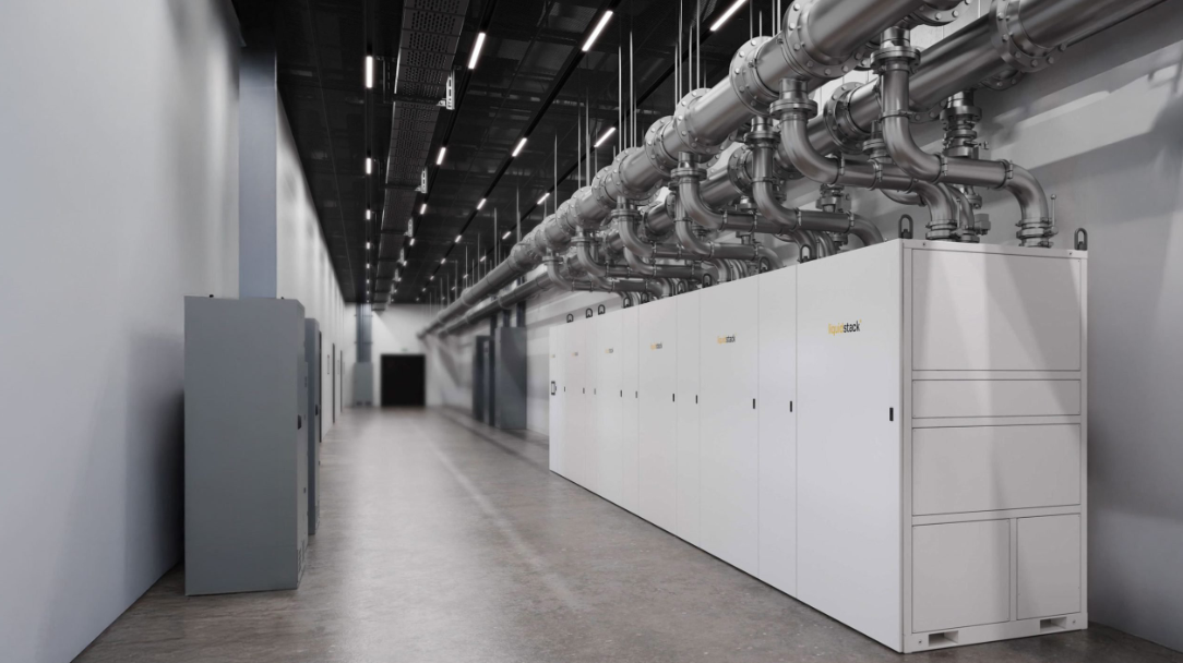 A row of industrial white cooling units in a corridor, connected to overhead silver piping in a modern data center.