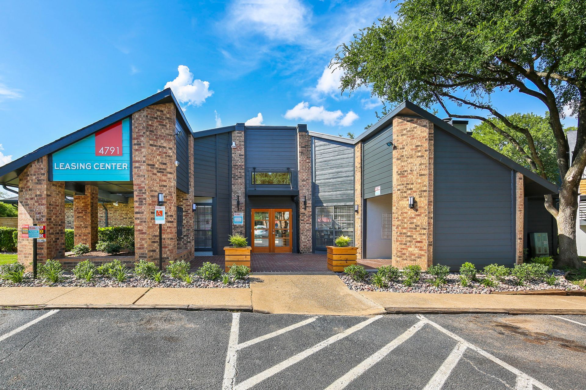 Apartment leasing office with brick and gray exterior. Teal sign reads 