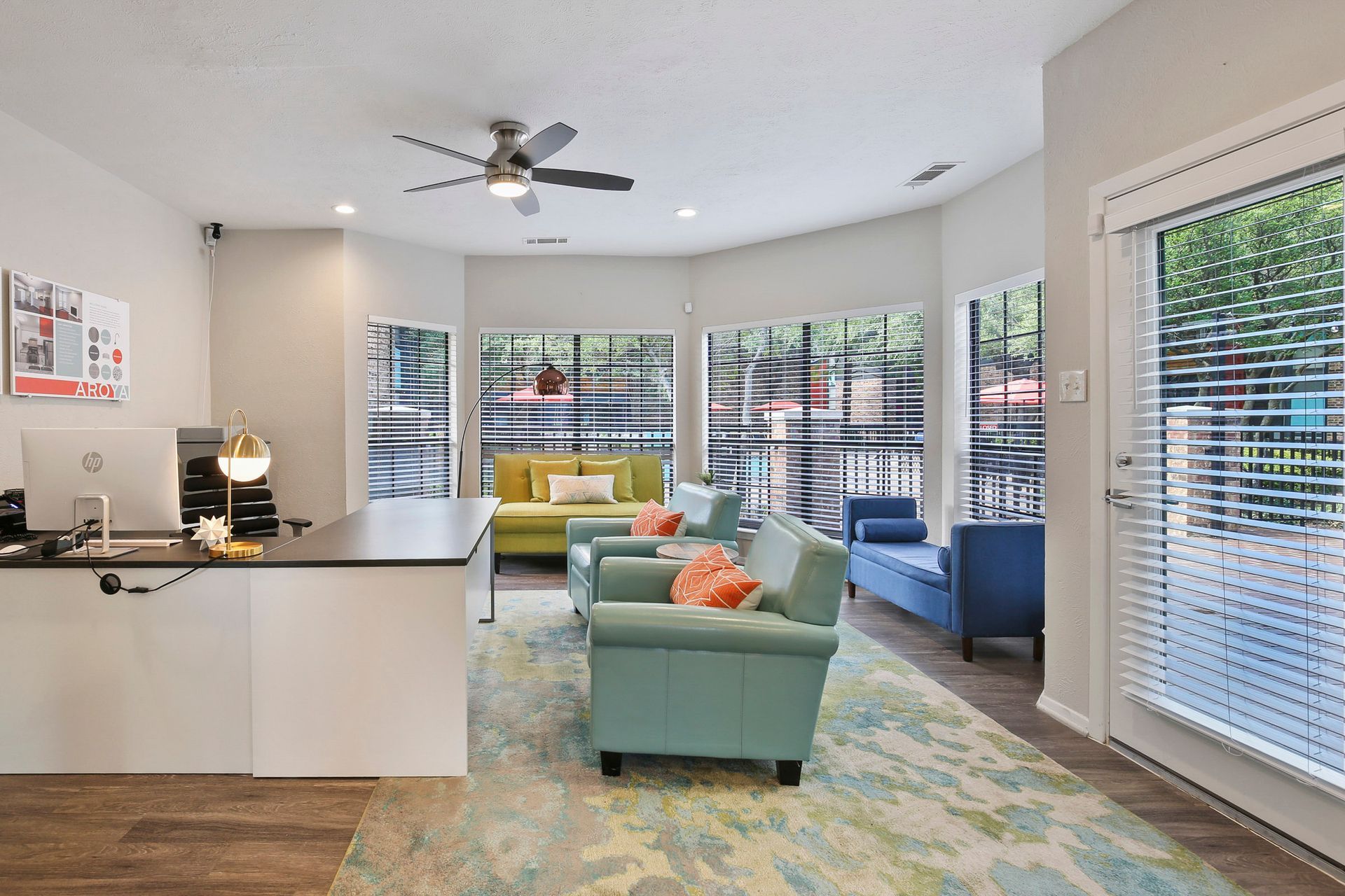 Reception area with a desk, seating, and large windows overlooking a wooded area.