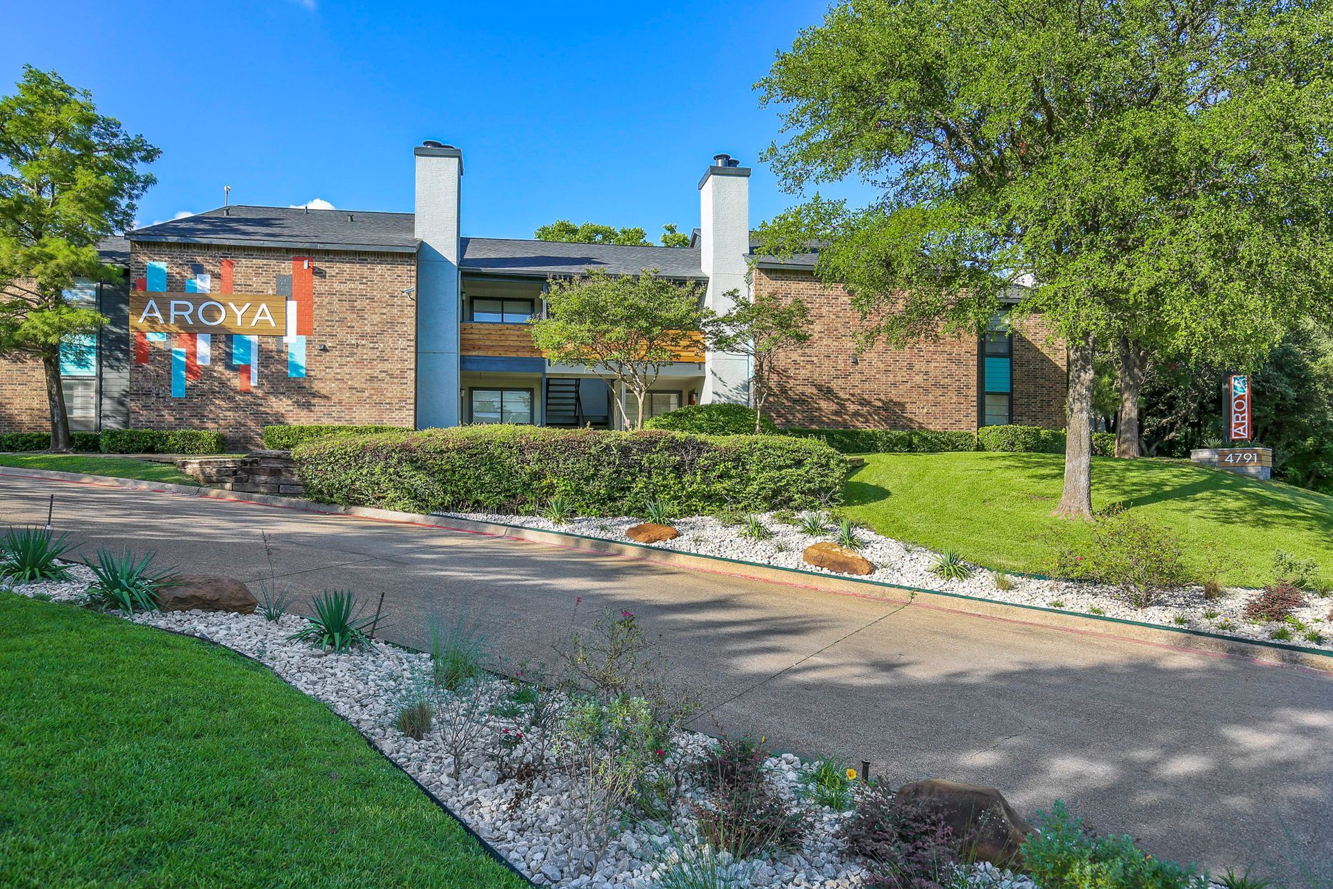 Apartment complex exterior with stone facade, two chimneys, and landscaped grounds.