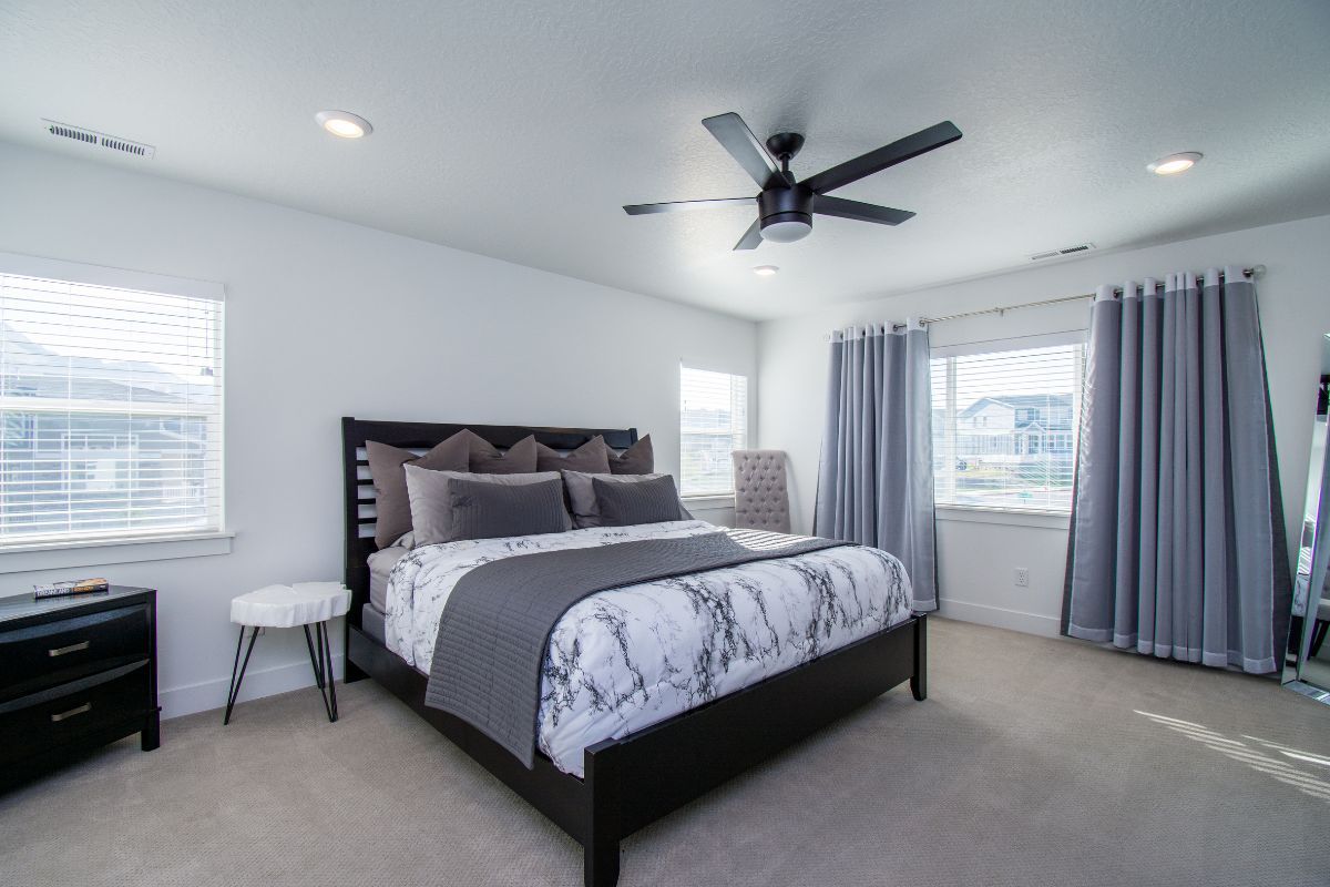 A bedroom with a large bed and a ceiling fan.