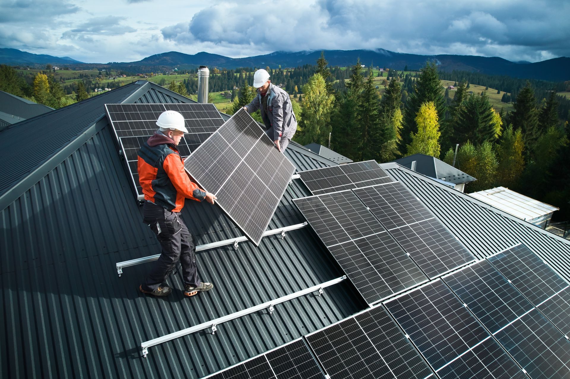 Workers installing solar panels on a roof in front