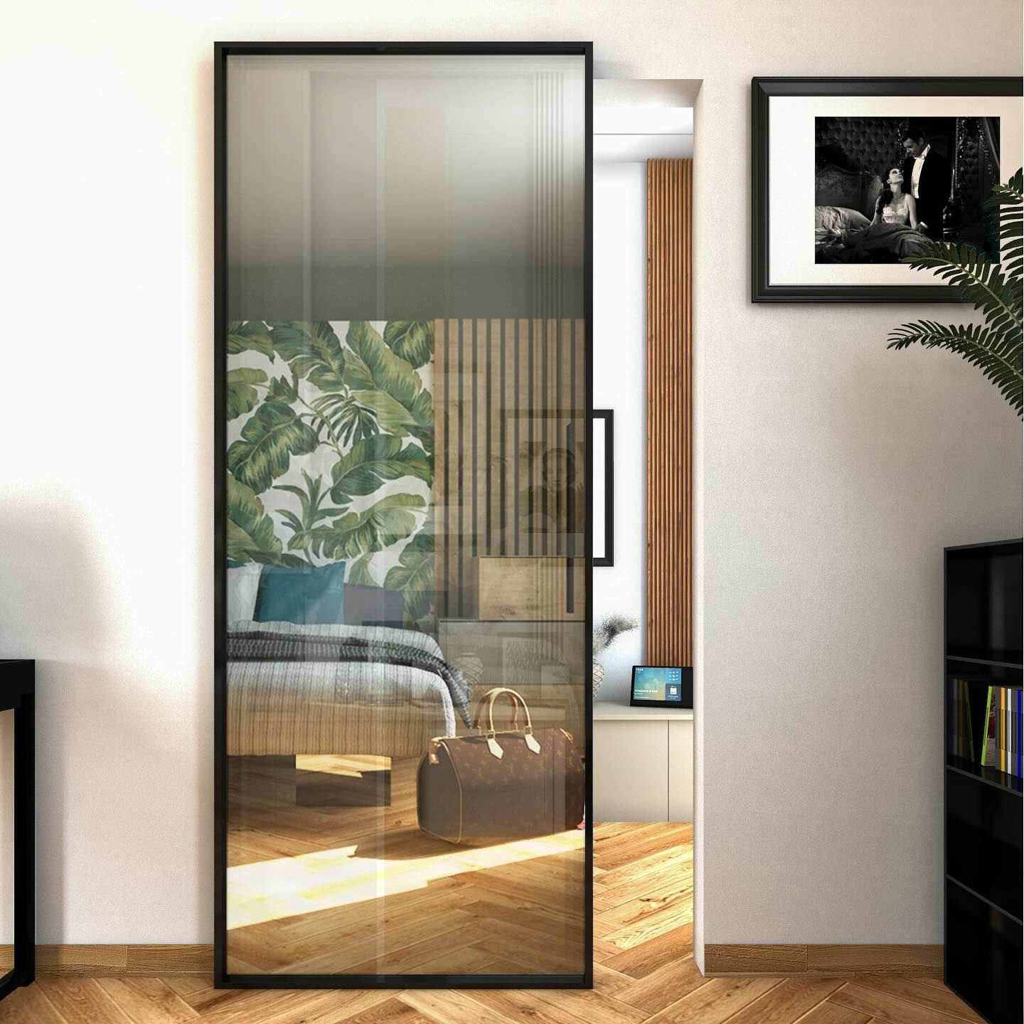 Camera da letto moderna con un grande specchio con cornice nera che riflette il letto, carta da parati a tema tropicale e luce del sole che illumina il pavimento in legno.