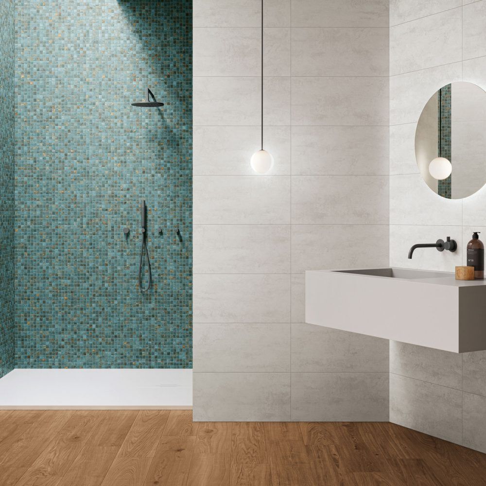 Bagno moderno con doccia a mosaico color verde acqua, pareti piastrellate di bianco, lavabo sospeso, specchio e pavimento in legno.