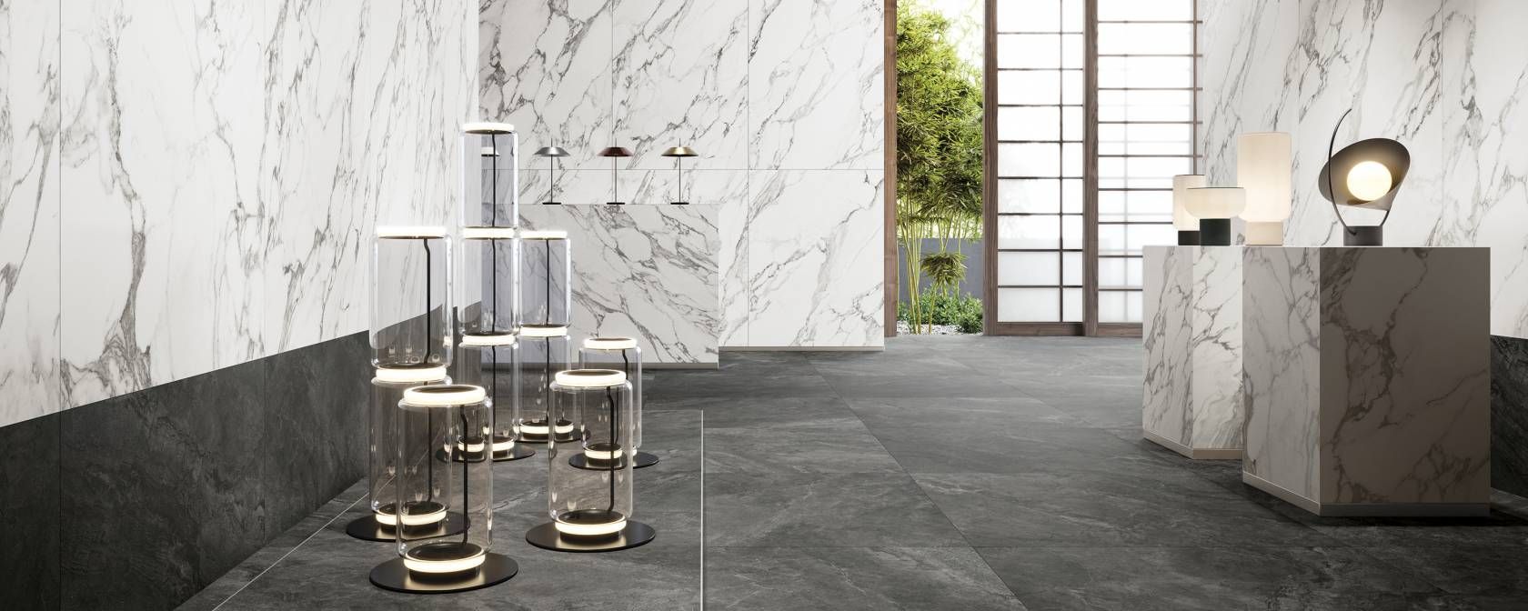 Showroom moderno con pareti in marmo, pavimento in pietra scura, vetrine cromate e un piedistallo in marmo con lampade da tavolo.