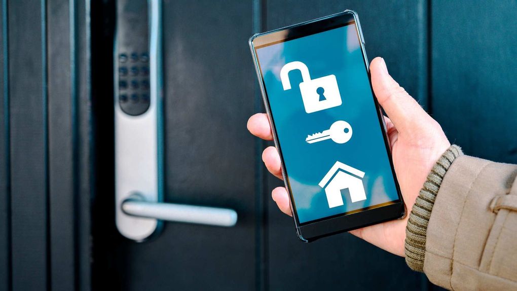 Una mano che tiene uno smartphone con le icone di sicurezza davanti a una serratura.