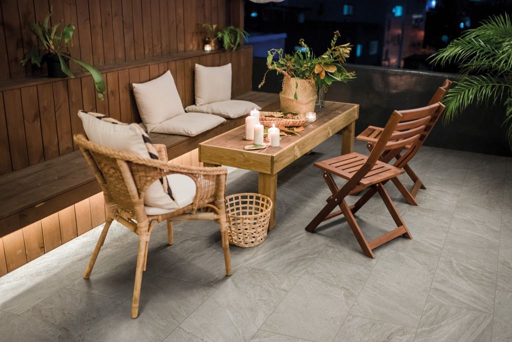 Accogliente patio esterno con sedie in vimini, tavolo in legno e calda illuminazione soffusa di sera.