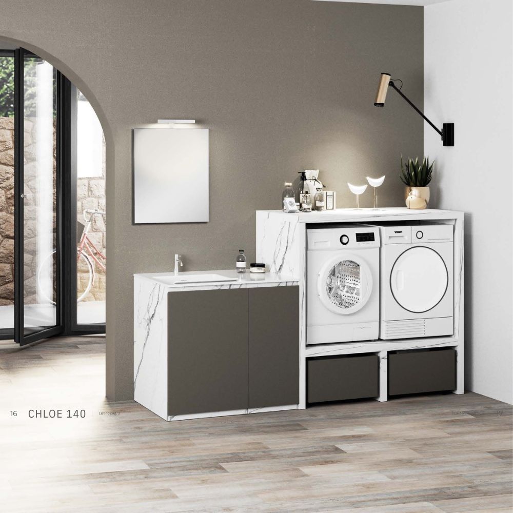 Bagno moderno con specchio rotondo sopra un lavabo a colonna bianco e piastrelle geometriche a parete, con una pianta sulla destra.