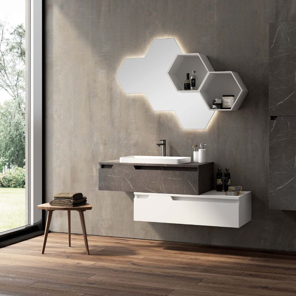 Bagno moderno con specchio esagonale illuminato, mobile lavabo sospeso e pavimento in legno accanto a una finestra.