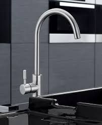Rubinetto da cucina in acciaio inox con beccuccio alto e curvo, installato sopra un lavello nero.