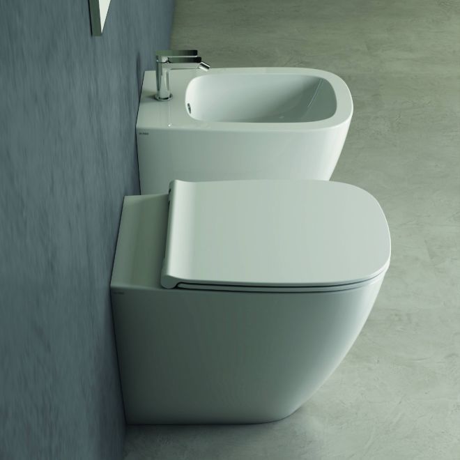 Due moderni WC bianchi in un bagno grigio, visti di lato.