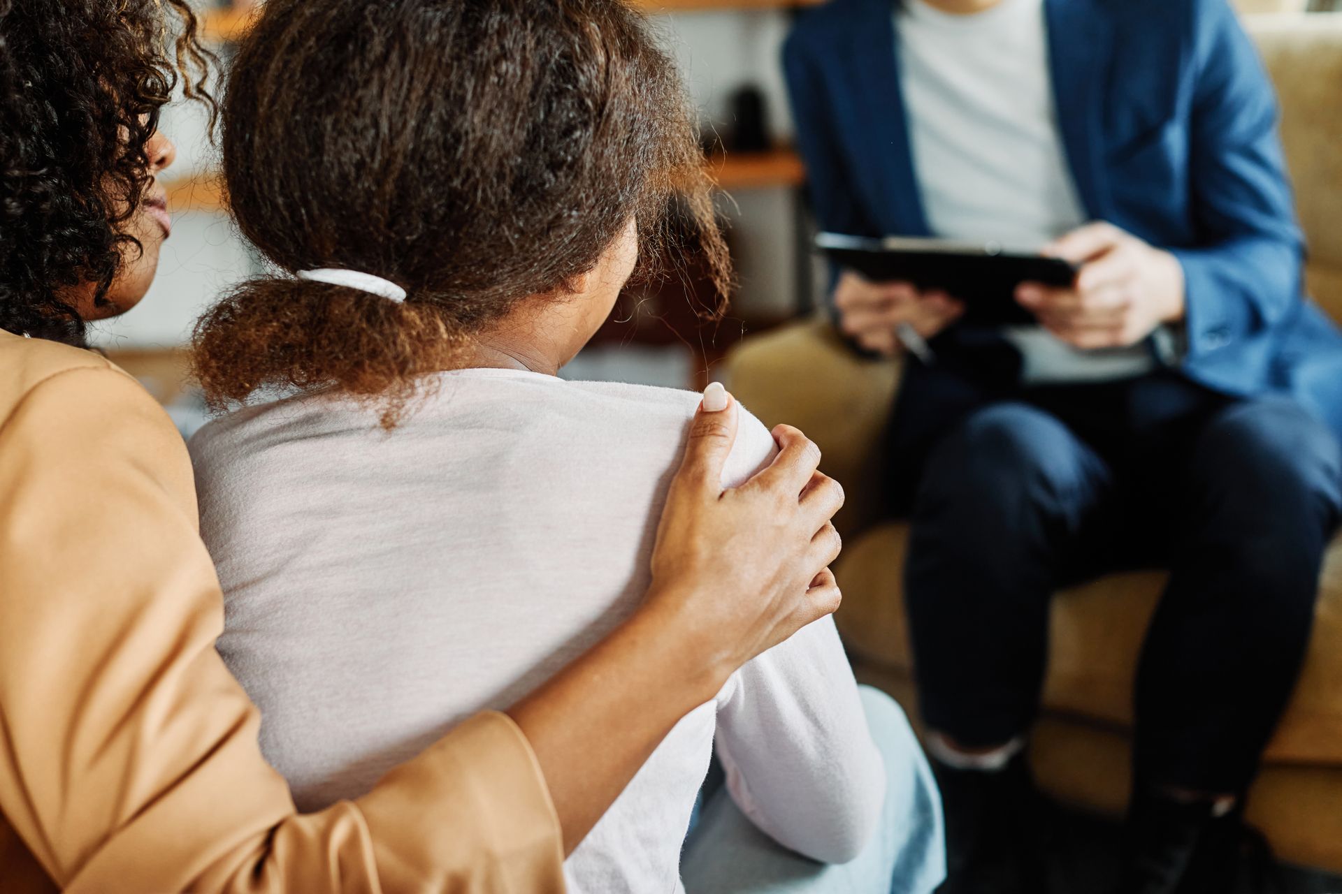 Mother and teenage daughter meeting with a therapist to discuss mental health and family concerns.