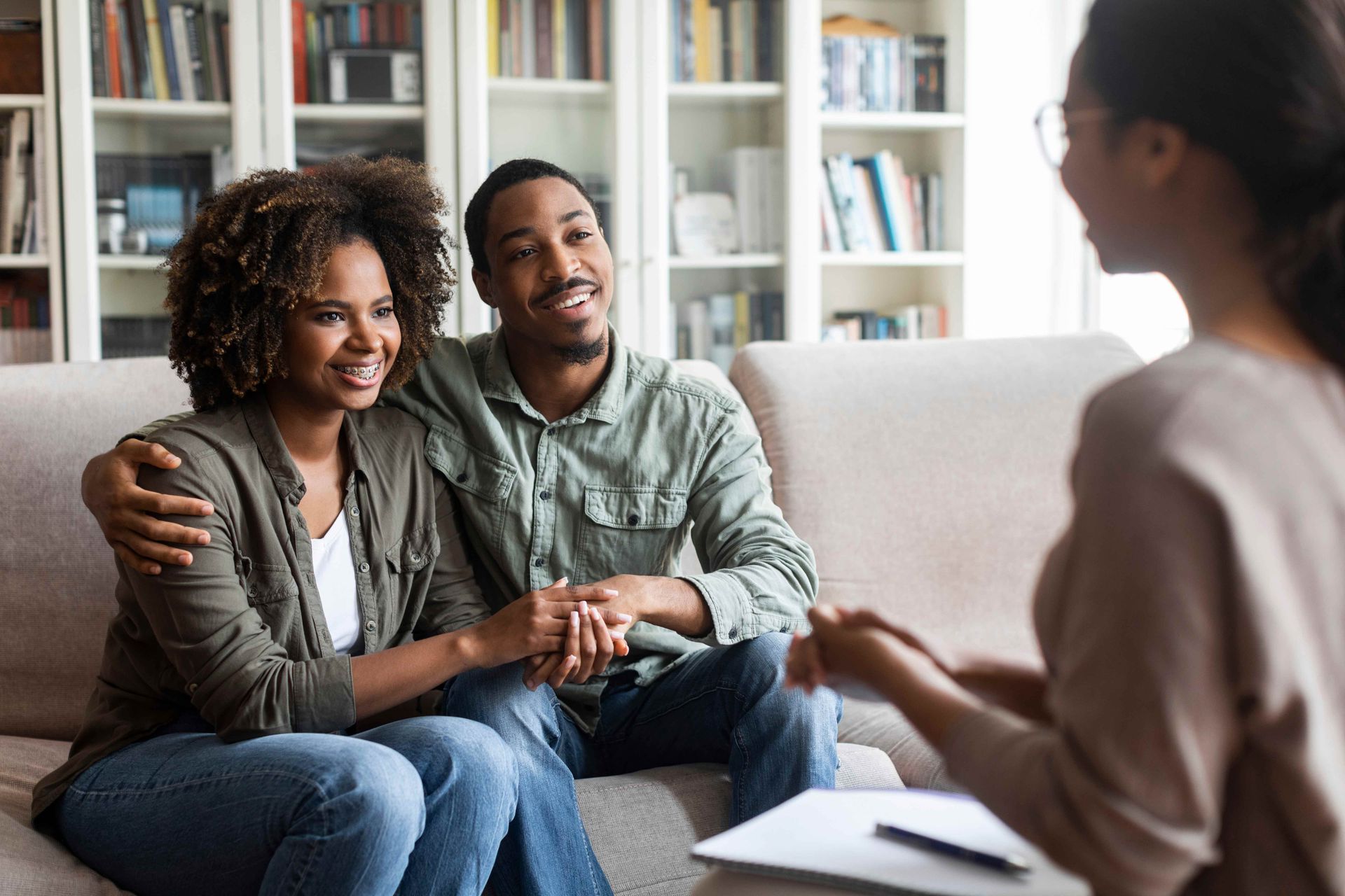 A couple in a therapy session with a counselor holding notes in a cozy living room. A couple in a therapy session with a counselor holding notes in a cozy living room.