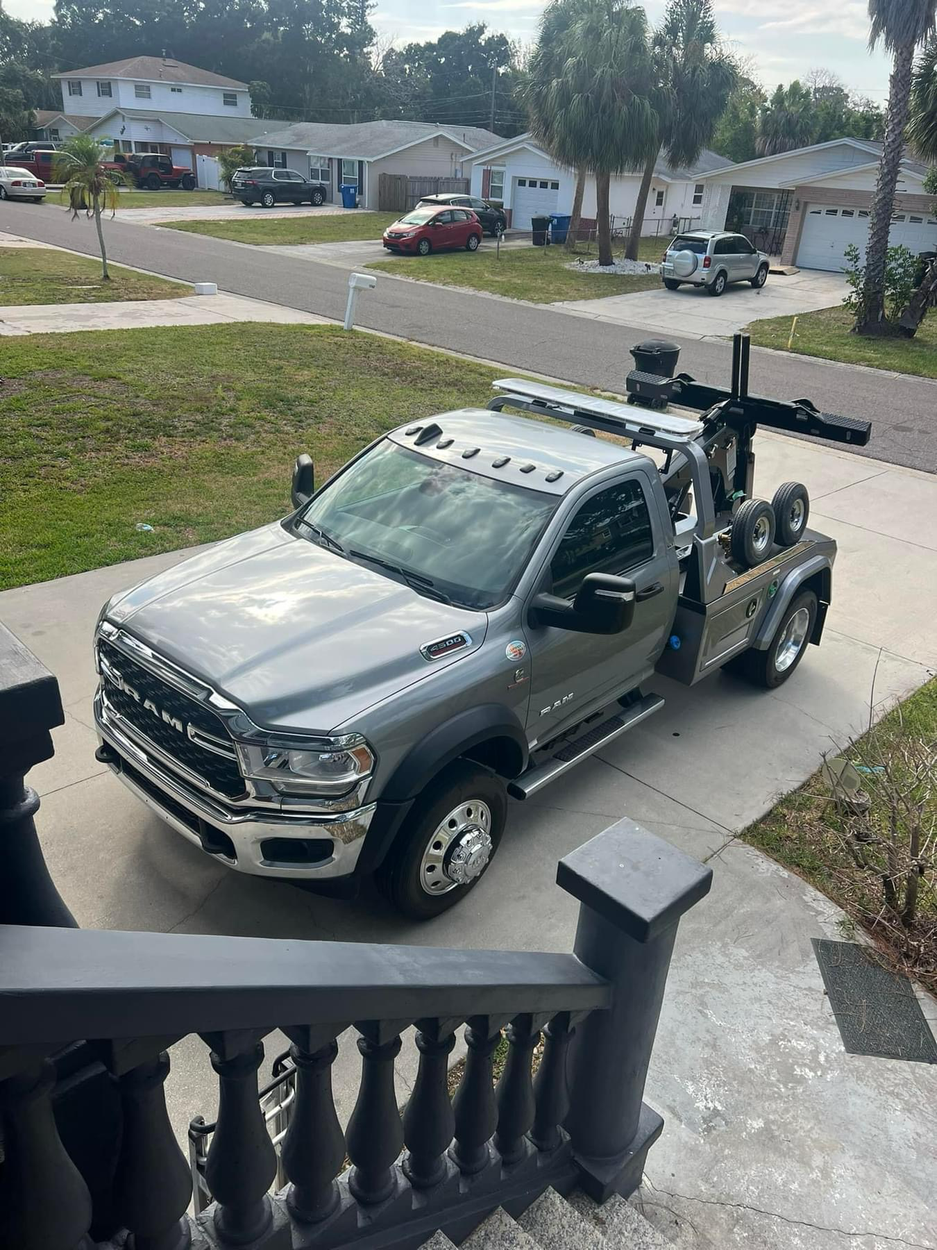 A tow truck is parked on the side of the road in front of a house.
