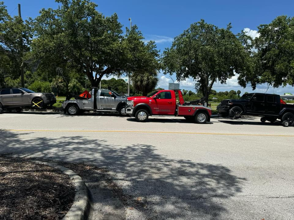 A row of tow trucks are parked on the side of the road.