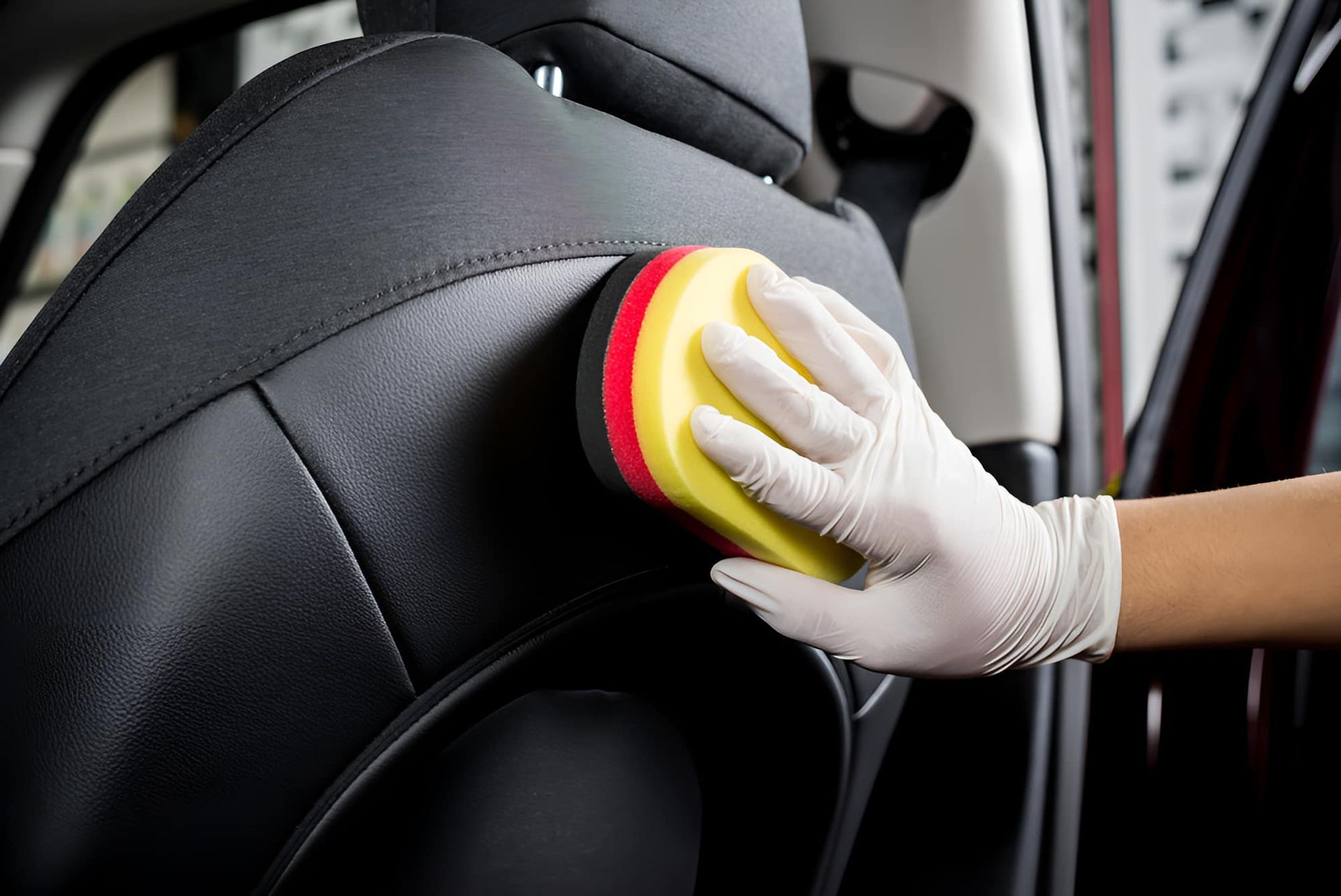 A Person Is Cleaning A Car Seat With A Sponge — Country Dirt Blasters Mobile Car Detailing In Murwillumbah, NSW