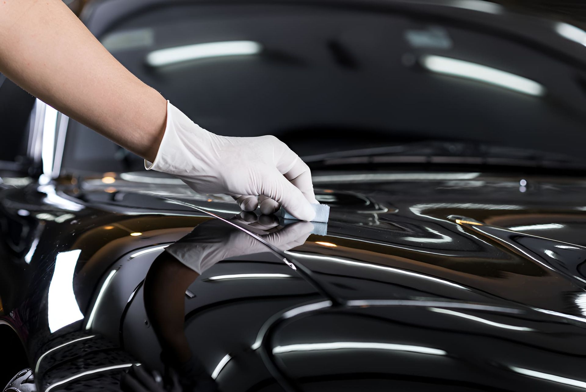 A Person Is Polishing The Hood Of A Black Car — Country Dirt Blasters Mobile Car Detailing In Murwillumbah, NSW