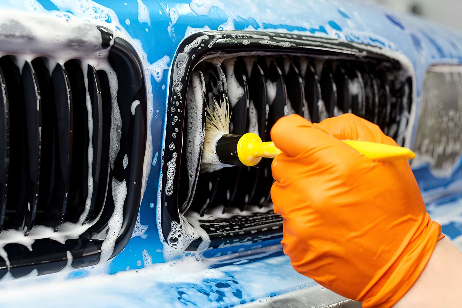 A Person Is Cleaning The Grill Of A Car With A Brush — Country Dirt Blasters Mobile Car Detailing In Murwillumbah, NSW