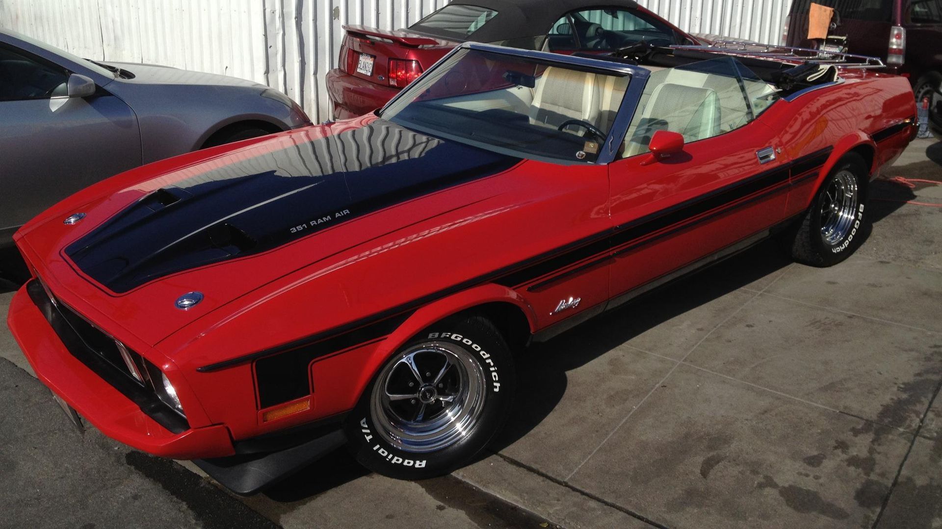 A red mustang convertible is parked in a parking lot
