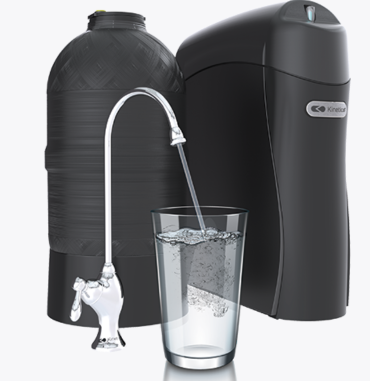 Person in blue overalls replacing water filter cartridges under a sink.
