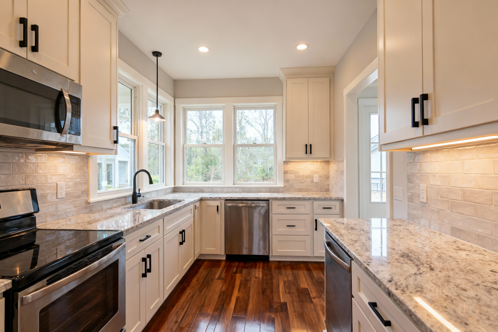 A bright kitchen featuring white shaker cabinets, stainless steel appliances, granite countertops, and hardwood floors.
