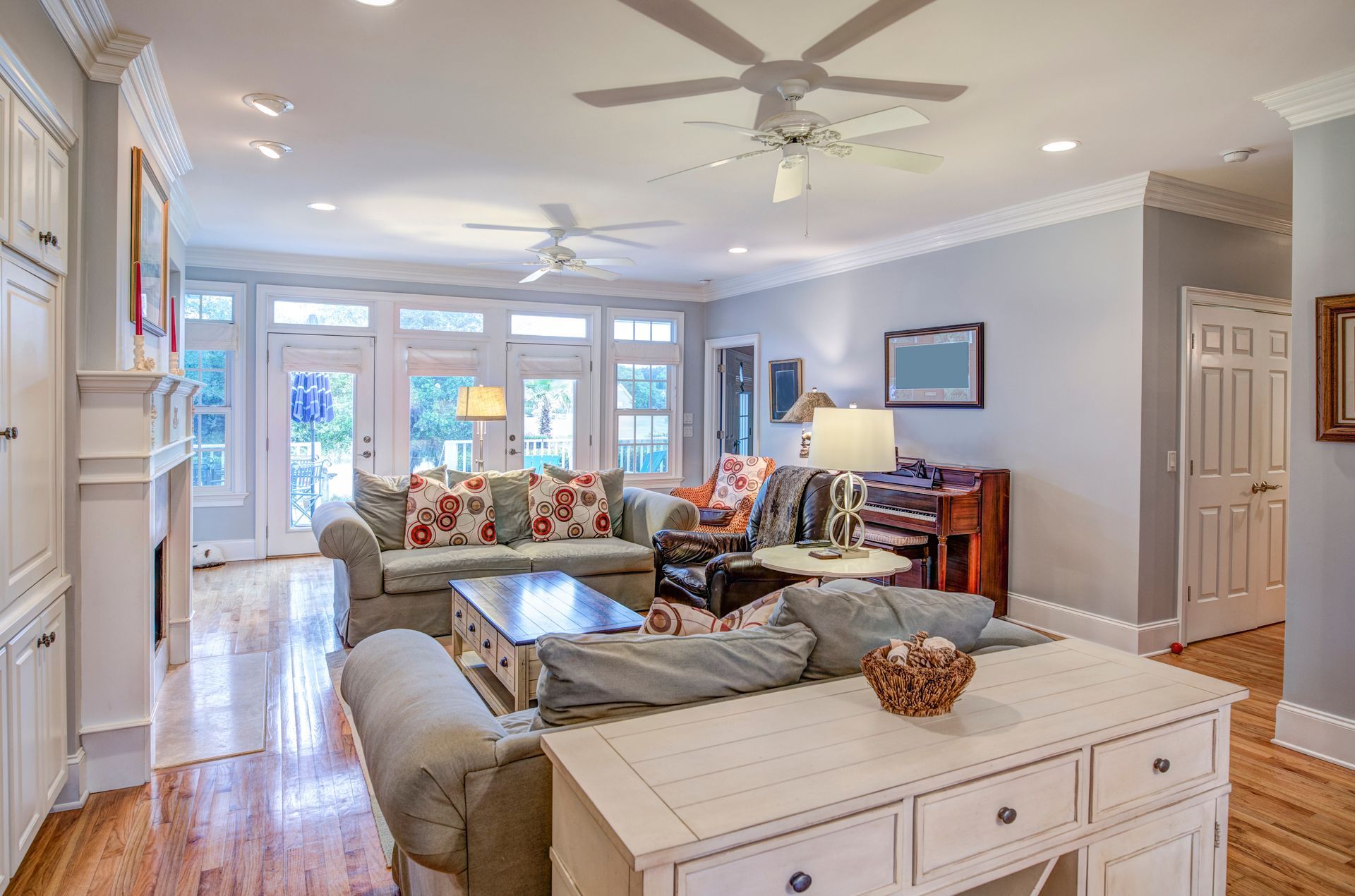 A bright, open-plan living room with light gray walls, white trim, two sofas, a coffee table, and hardwood floors.