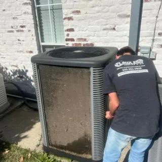 Flawless Heating and Air LLC - A man in a black shirt is standing next to a dirty air conditioner.