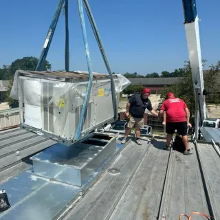 Flawless Heating and Air LLC - A crane is lifting a large box on top of a roof.