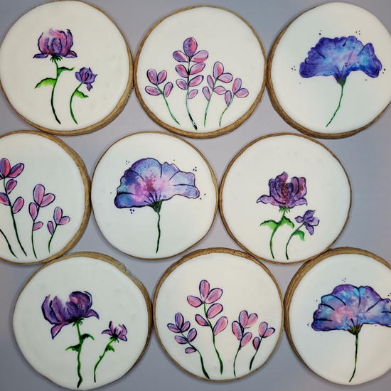 Nine round sugar cookies arranged in a grid, each hand-painted with purple and blue watercolor-style floral designs.