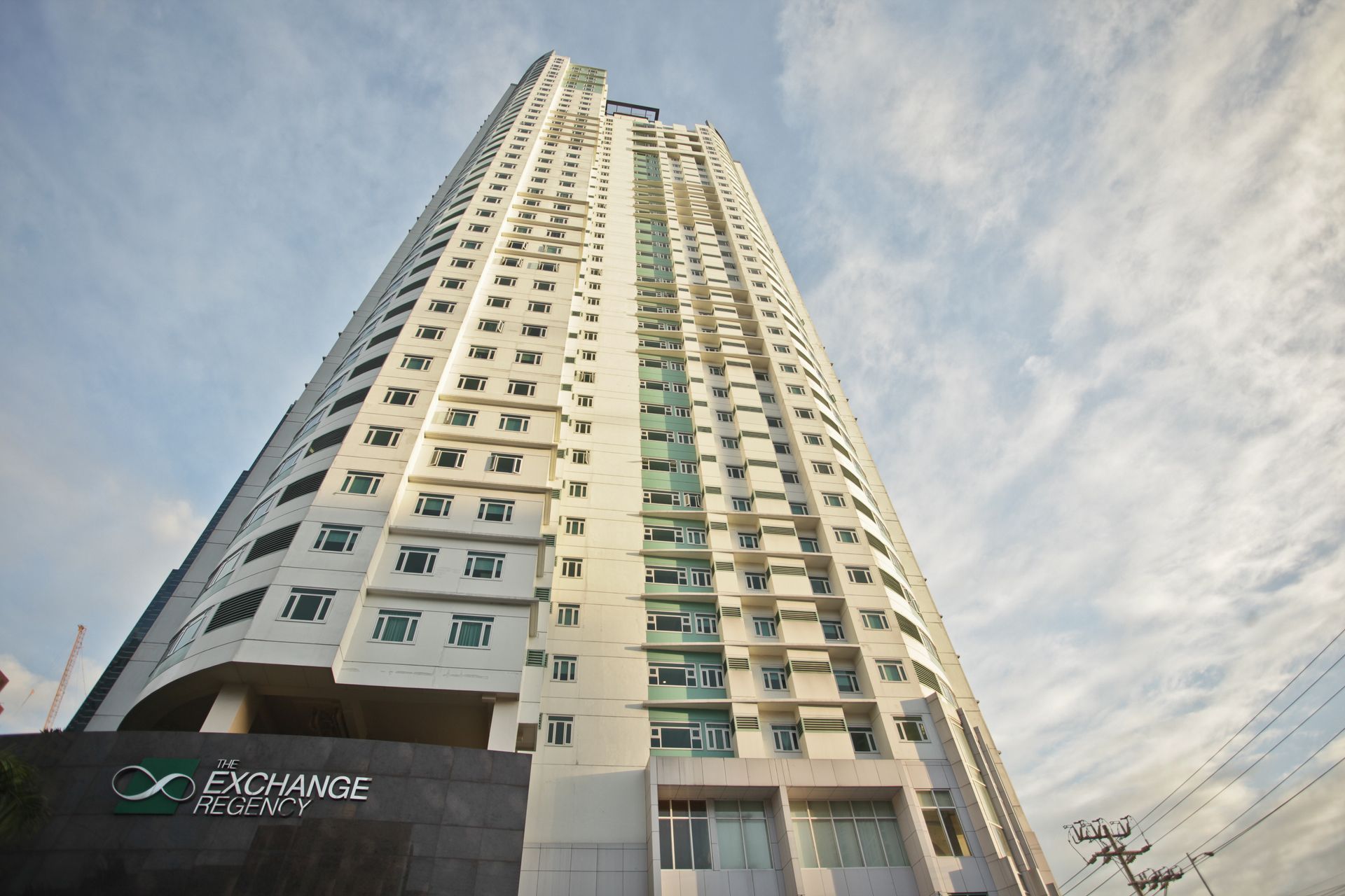 Tall white high-rise building seen from below against a cloudy sky