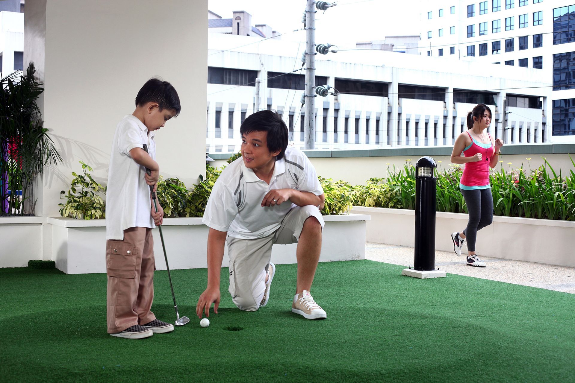 A man and two children are playing golf on a lush green lawn