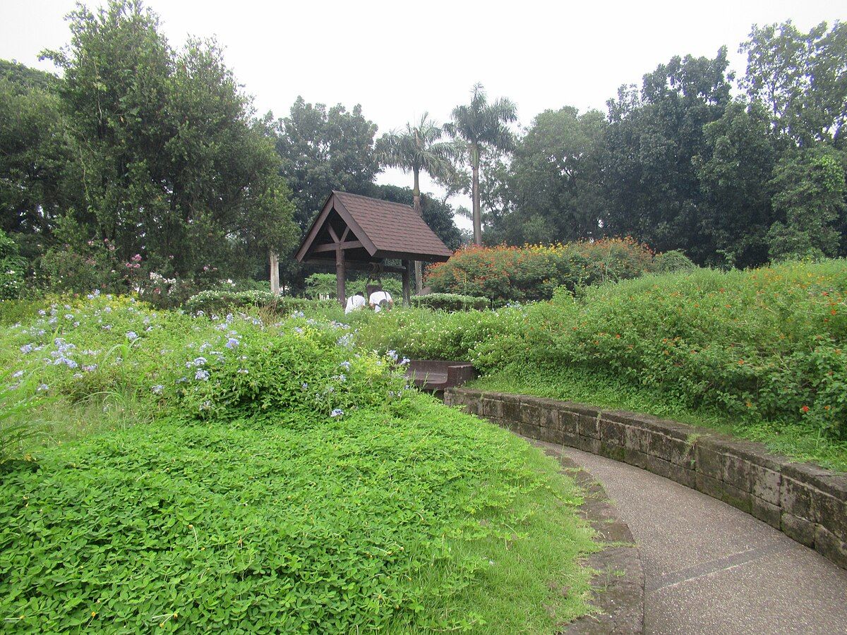 Lush garden with wooden gazebo and colorful flowers near Makati hotel