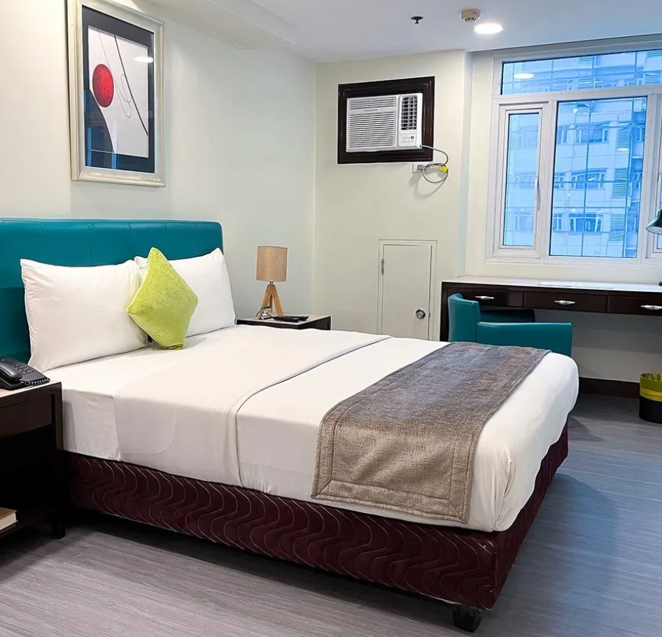 A hotel room with a large bed and a window