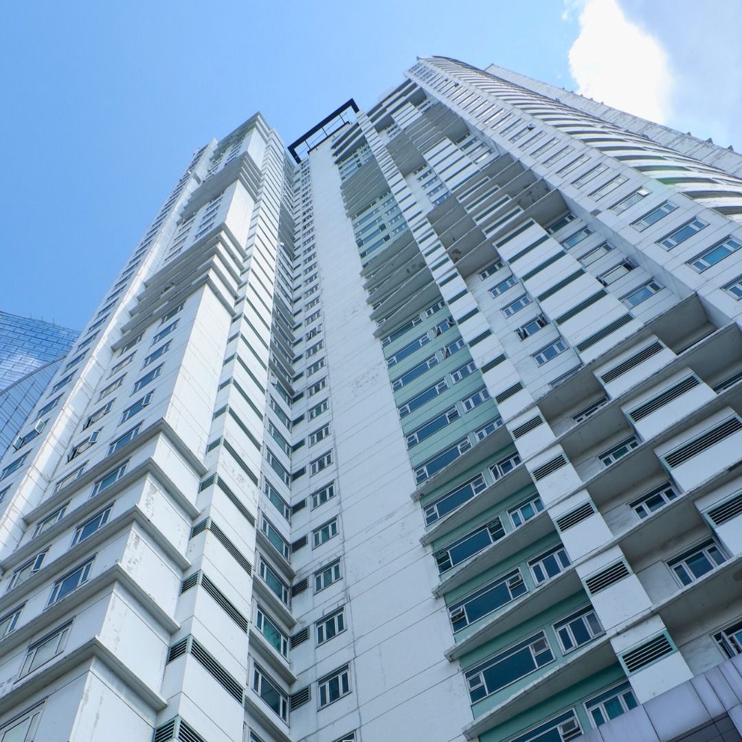 Low-angle view of a tall white high-rise apartment building against a blue sky