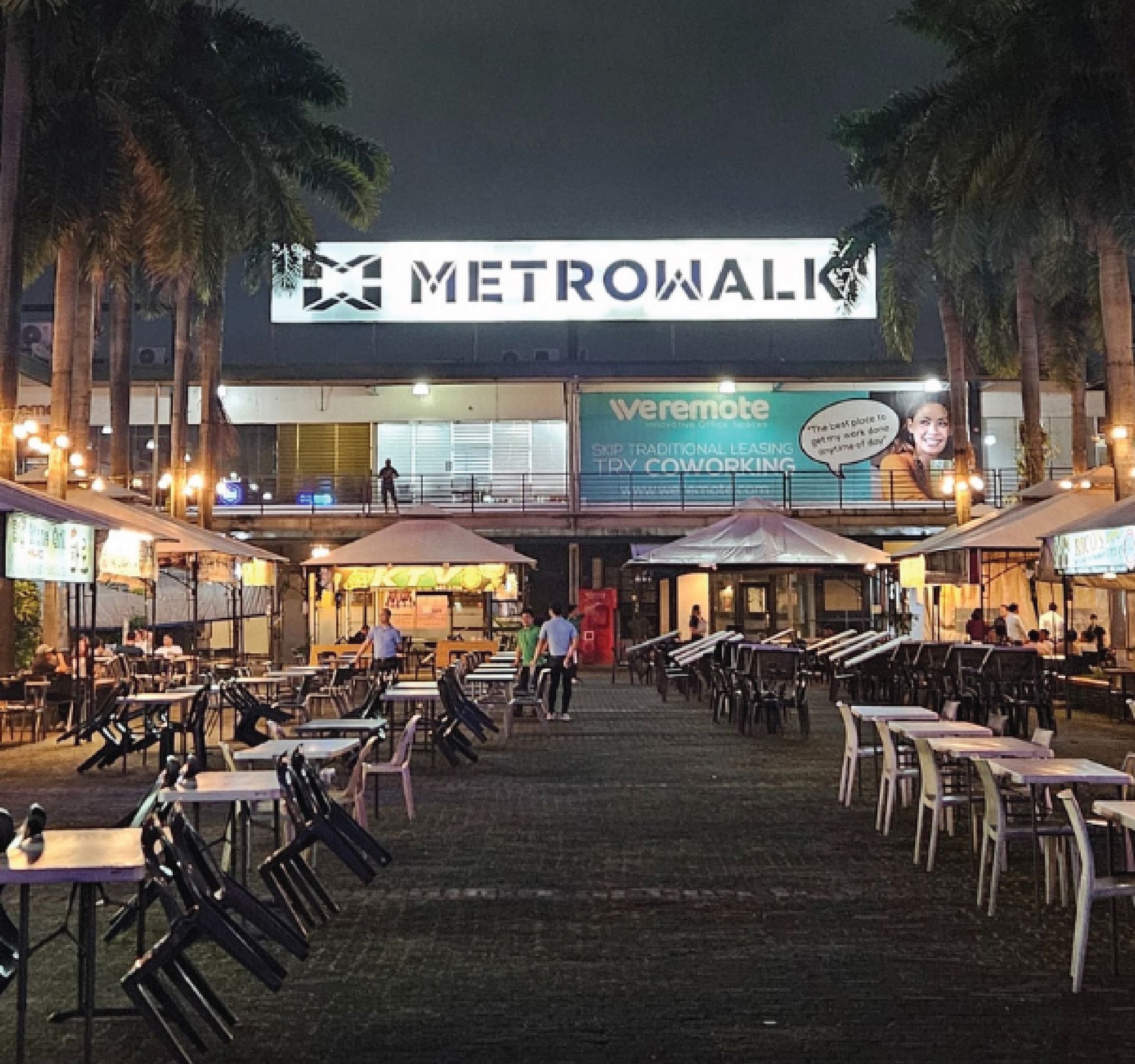 A row of tables and chairs in front of a building that says metrowalk
