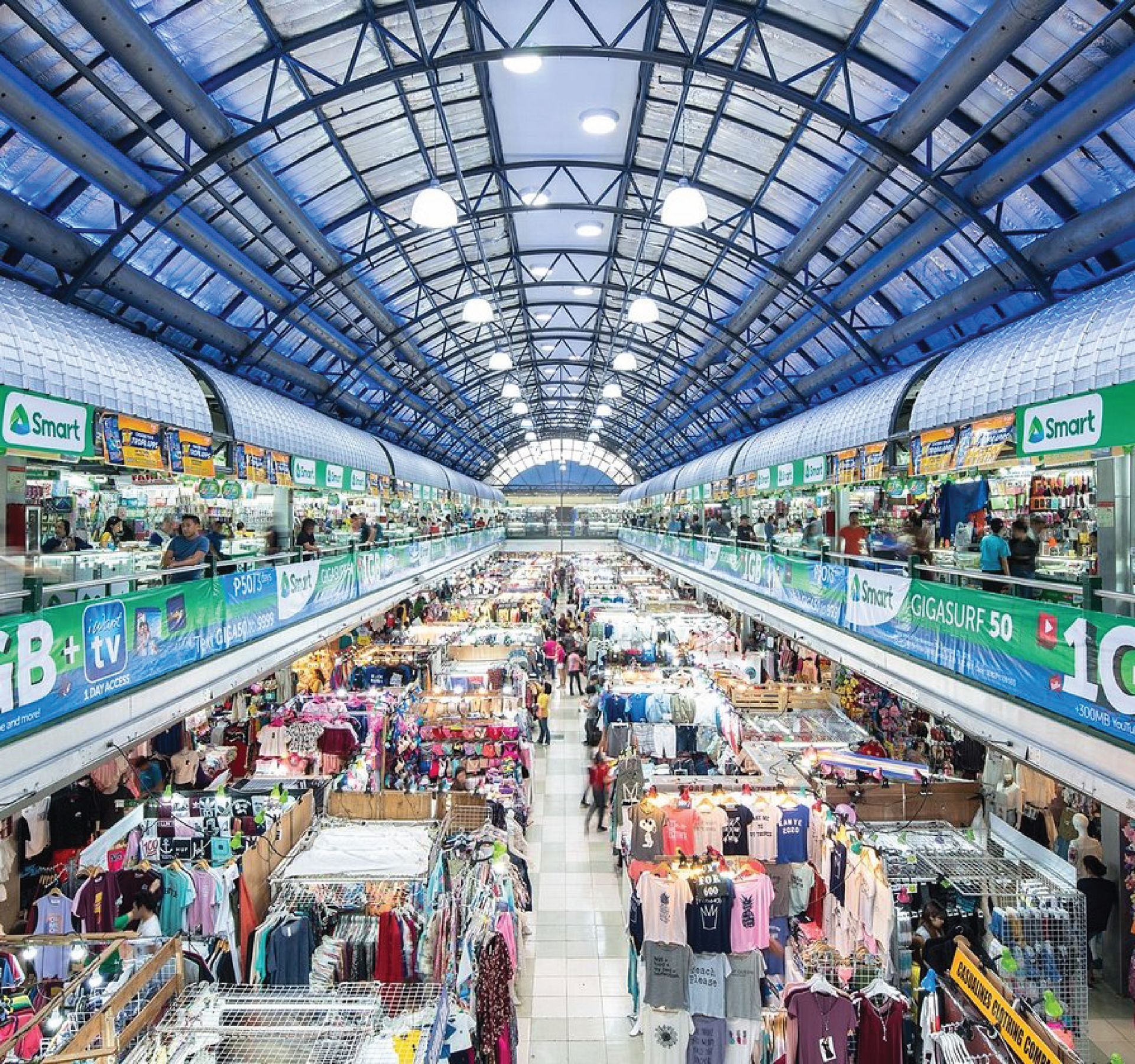 A large shopping mall filled with lots of clothes and people.