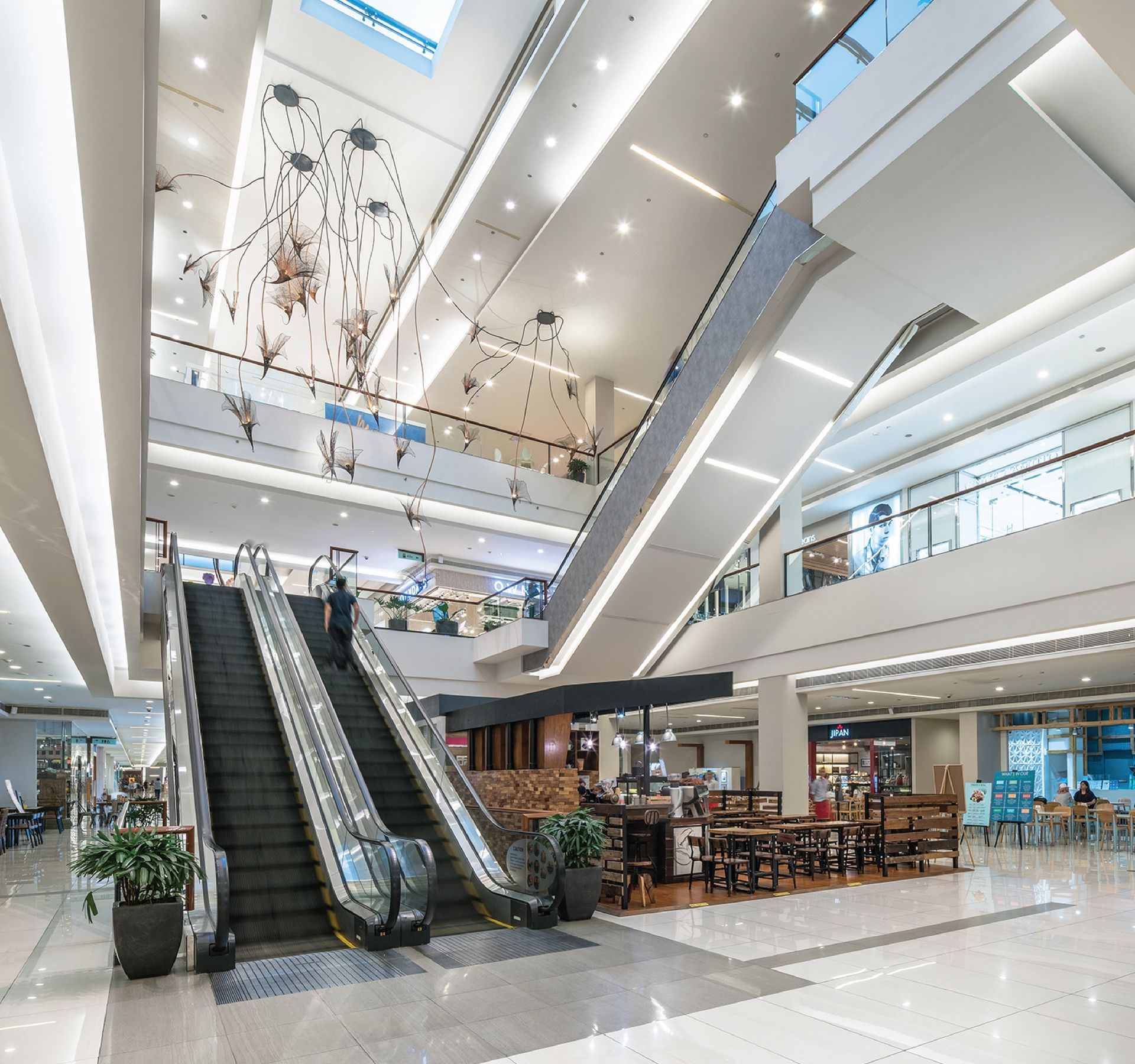 An escalator in a large building with tables and chairs