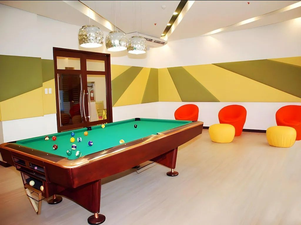 Pool table in game room, with colorful walls, seating, and overhead lights.