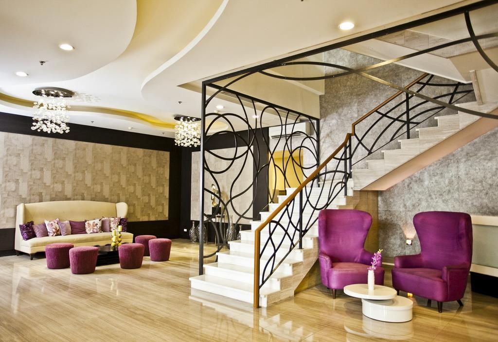 Elegant hotel lobby with purple chairs and ornate staircase at The Exchange