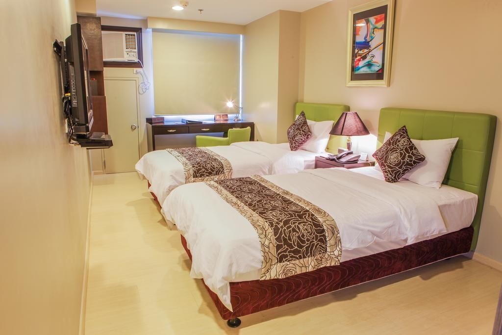 A hotel room with two beds , a desk and a television.