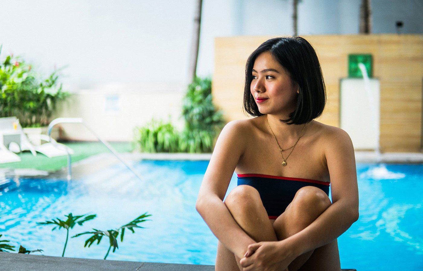 Woman in navy bandeau bikini sitting poolside at Exchange Regency Makati