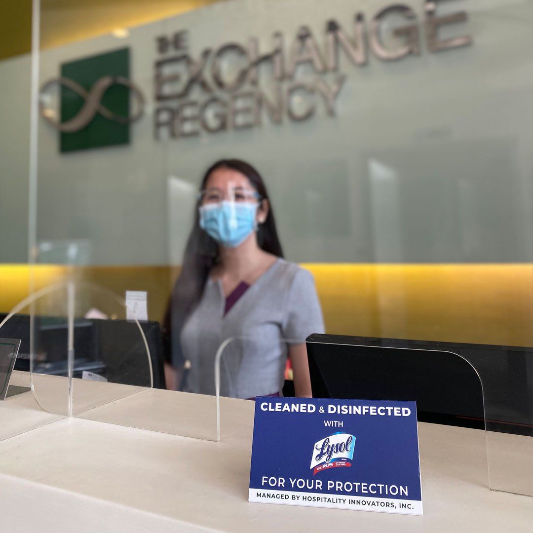 A woman wearing a mask stands behind a counter at the exchange regency