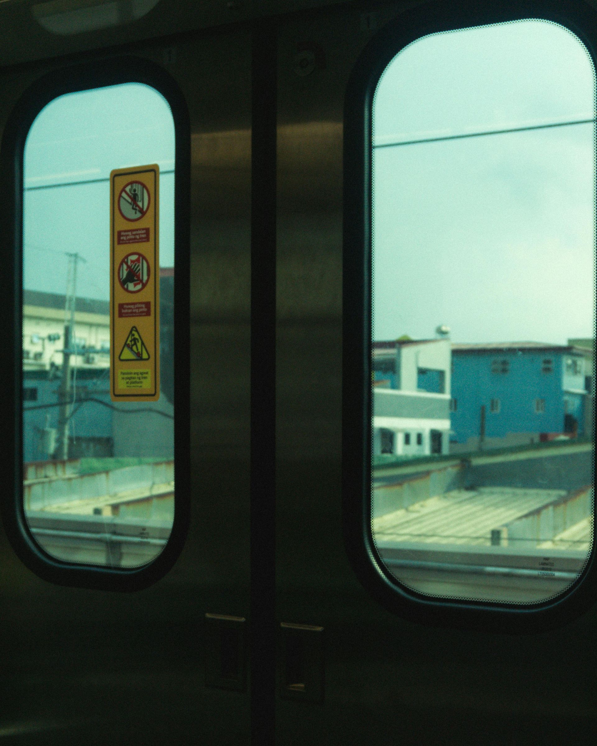 View of Makati cityscape from MRT train window with safety signs
